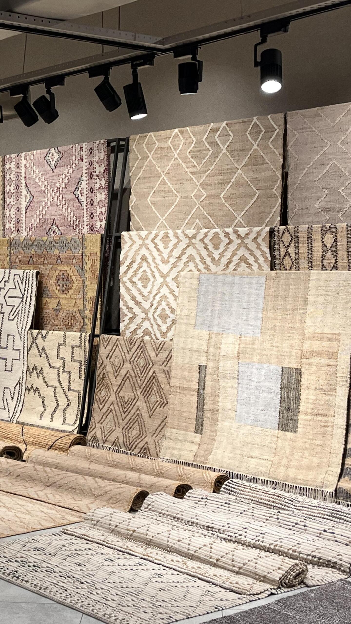 A display of multiple patterned and textured rugs, primarily in neutral and earthy tones, illustrating the evolution of rug design. This visual highlights how digital transformation in the rug industry enables advanced design techniques, improved materials, and streamlined production processes, merging tradition with technology.