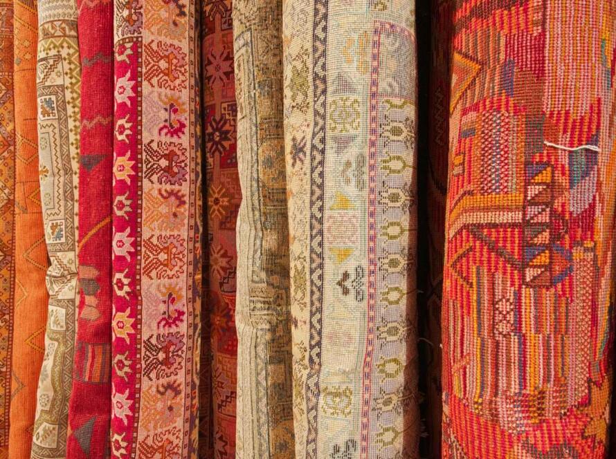 Rows of rolled colorful rugs showcasing intricate patterns and durable materials, ideal for understanding which rugs last the longest.