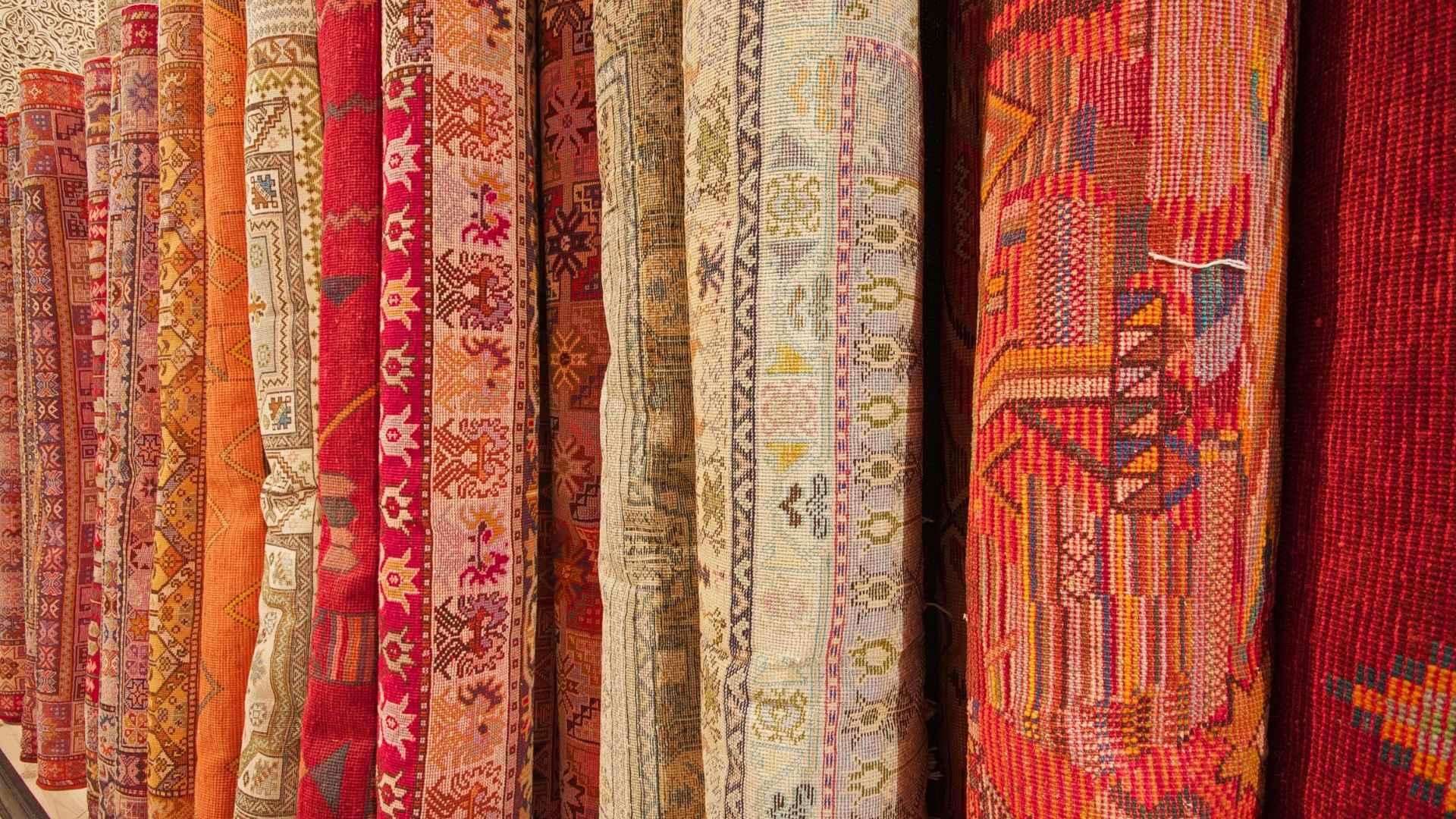 Rows of rolled colorful rugs showcasing intricate patterns and durable materials, ideal for understanding which rugs last the longest.