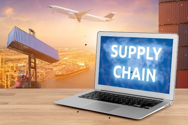 Supply chain concept featuring a laptop displaying 'SUPPLY CHAIN' on the screen, with a backdrop of shipping containers, an airplane, and a crane lifting cargo