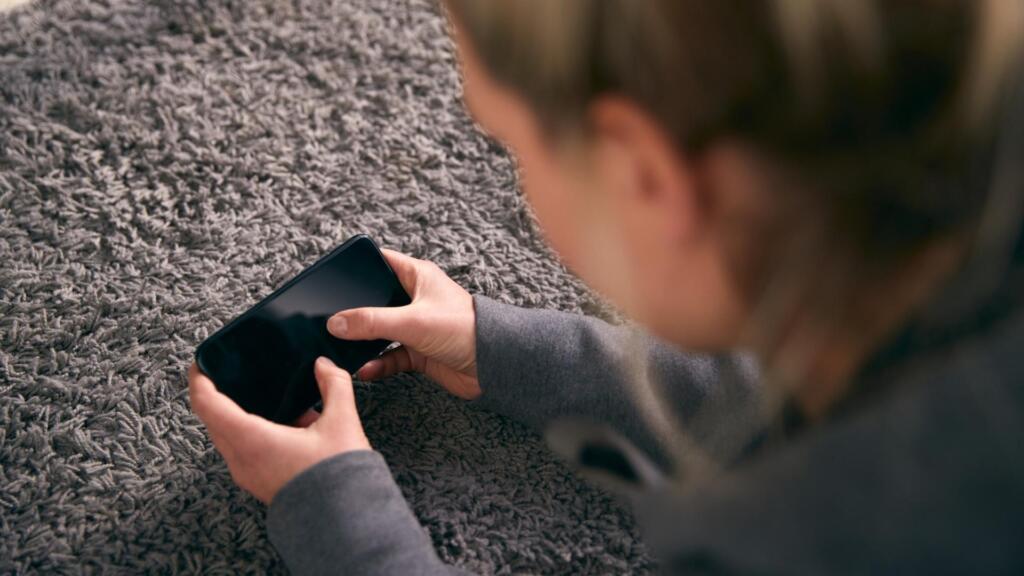 A person sitting comfortably on a plush gray rug, holding a smartphone, showcasing a relaxed and cozy setting ideal for casual browsing or online shopping.






