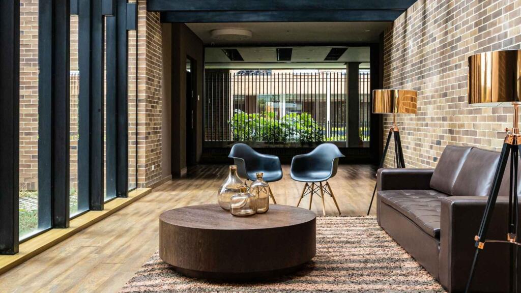 Modern living room with a textured area rug beneath a round coffee table, complementing the contemporary furniture and creating a cozy, stylish ambiance.
