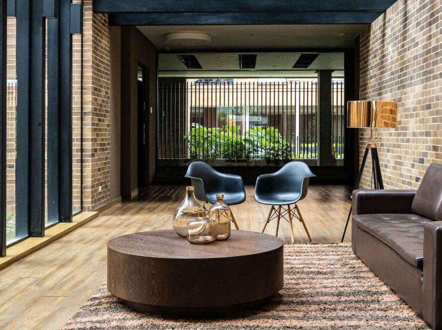 Modern living room with a textured area rug beneath a round coffee table, complementing the contemporary furniture and creating a cozy, stylish ambiance.