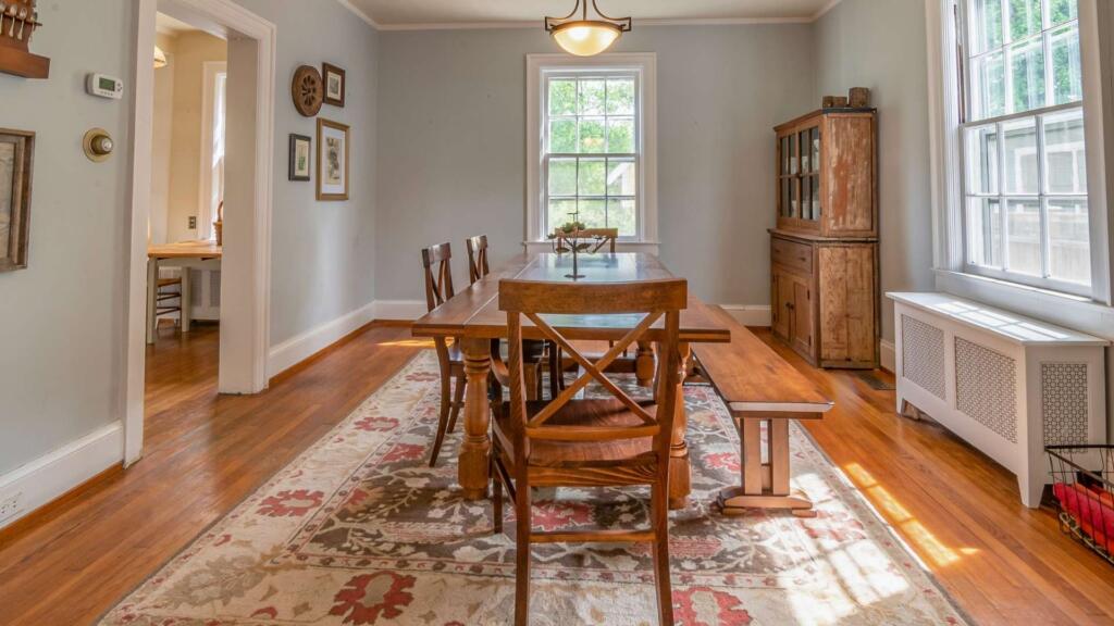 A traditional area rug with floral patterns placed under a wooden dining table, enhancing the cozy and classic look of the dining room space.