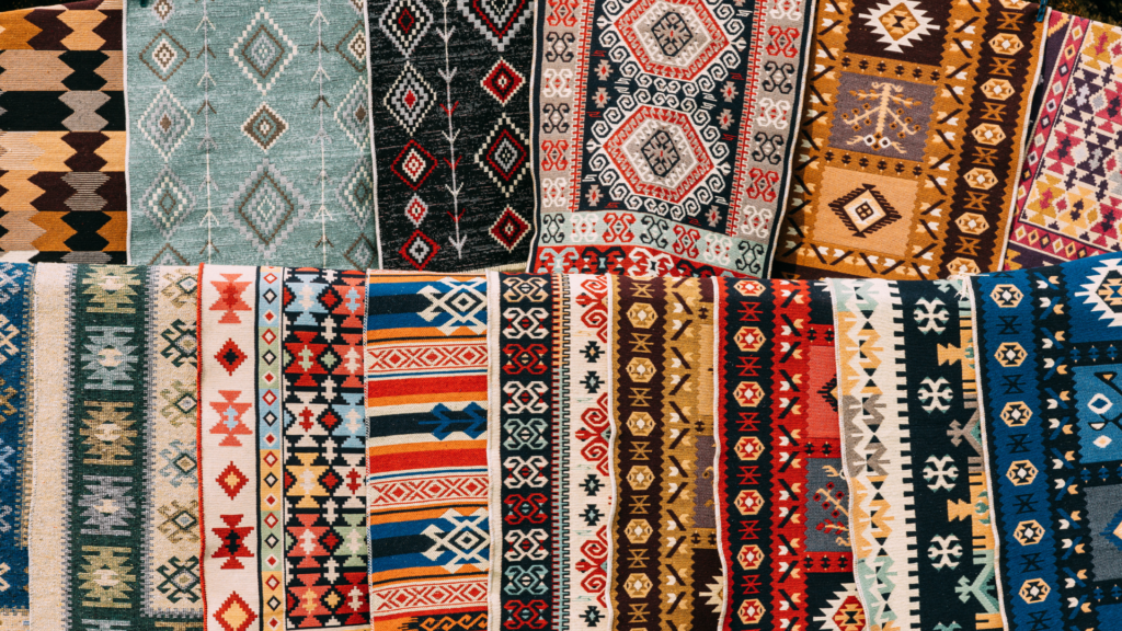 A colorful display of traditional woven rugs with intricate patterns.
