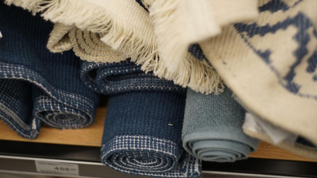 Rolled up cotton rugs in various shades of blue and white.