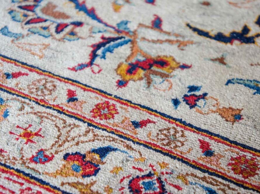 Detailed view of a handwoven rug with intricate floral patterns in various colors.