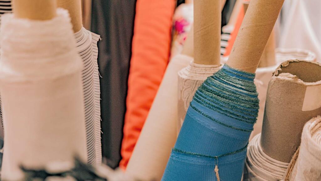 A variety of colorful fabric rolls neatly organized on a shelf.