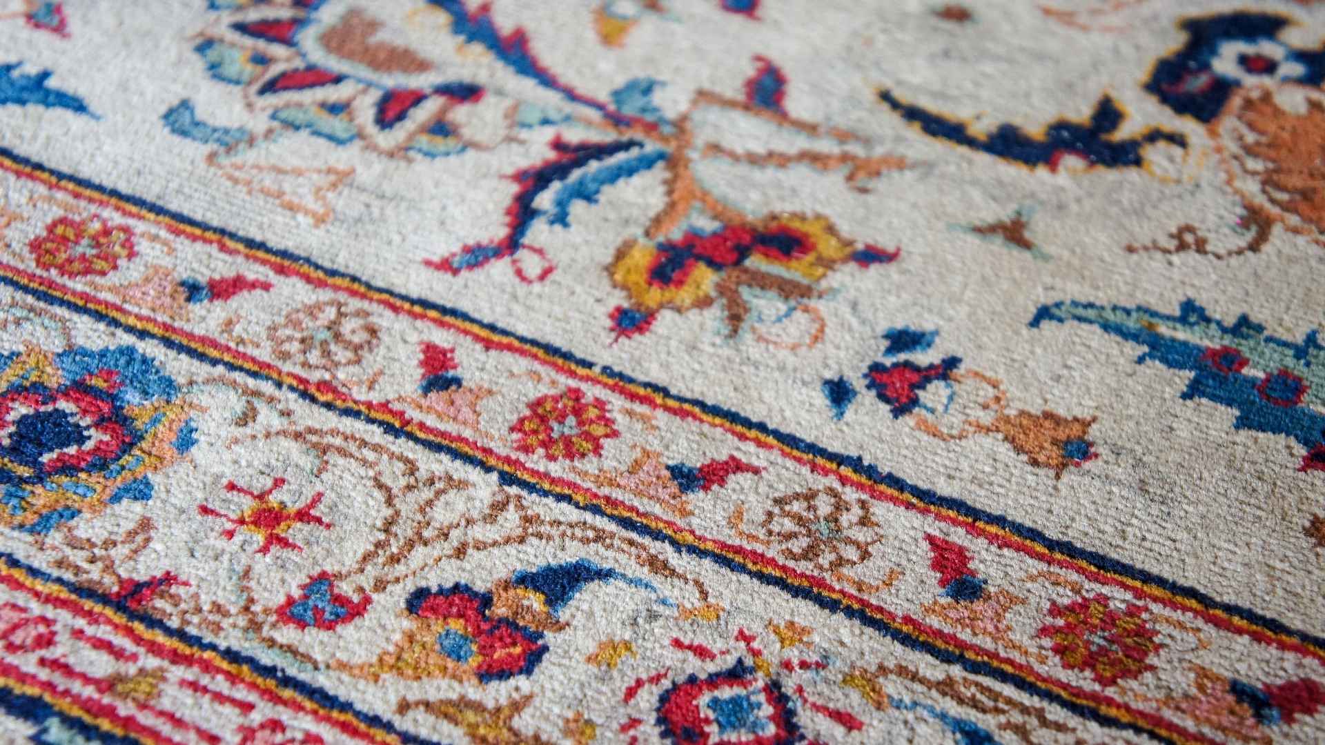 Detailed view of a handwoven rug with intricate floral patterns in various colors.