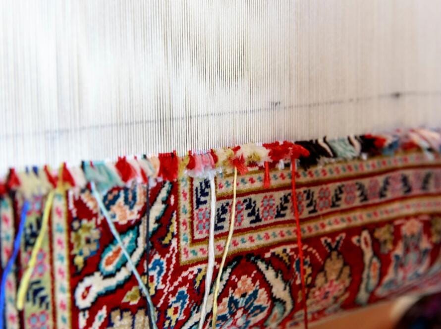Close-up of a traditional carpet weaving process, showcasing intricate patterns and vibrant colors, representing the importance of choosing the right commercial carpet manufacturer for quality craftsmanship.