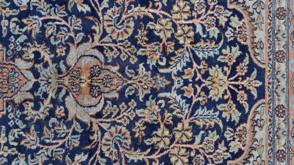 Luxurious custom-designed carpet featuring intricate floral patterns on a deep blue background, crafted by a premium custom-designed carpets manufacturer.