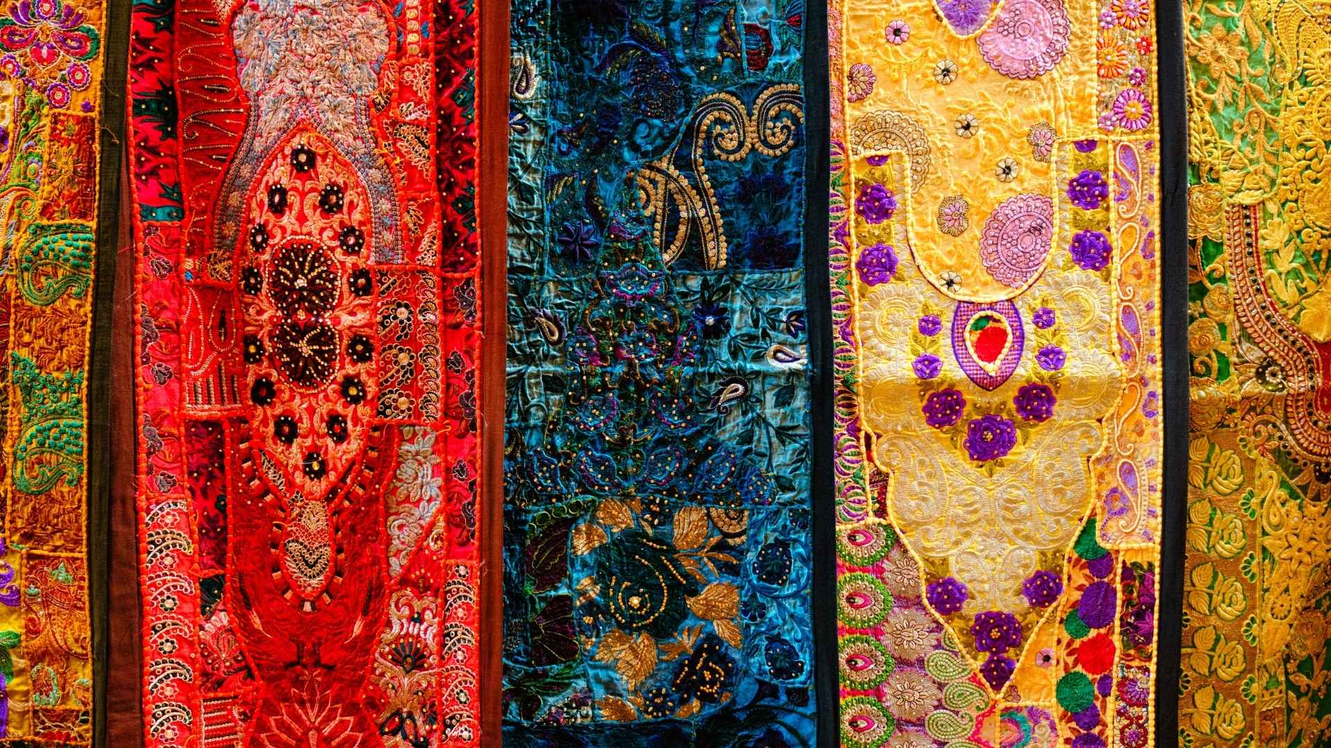 "A vibrant display of traditional Indian embroidered wall hangings in rich colors and intricate designs."