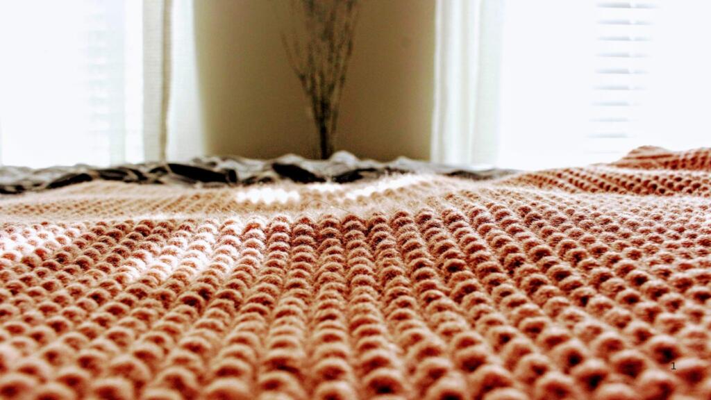 "A cozy knitted wool rug in warm tones, laid in a sunlit room, highlighting the versatility and natural beauty of wool products crafted by New Zealand manufacturers."
