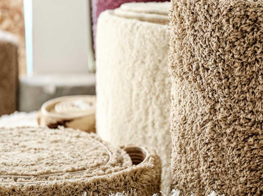 Close-up of rolled carpet flooring in various textures and colors, available at wholesale prices for residential and commercial use.