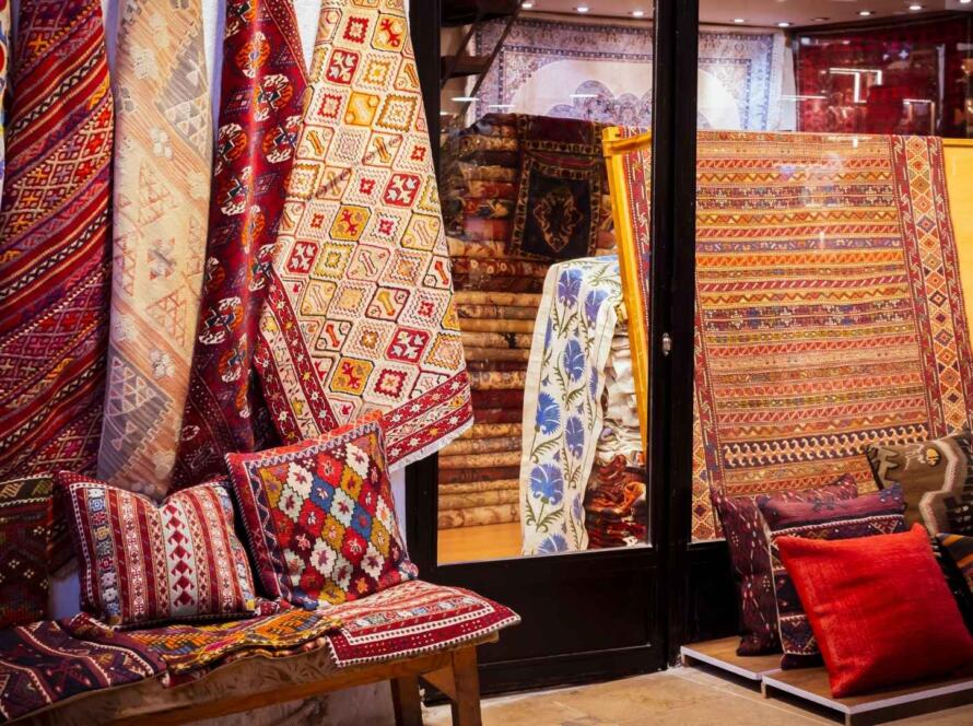 Colorful custom commercial rugs and pillows displayed in a showroom, showcasing intricate patterns and craftsmanship by a custom commercial rugs manufacturer