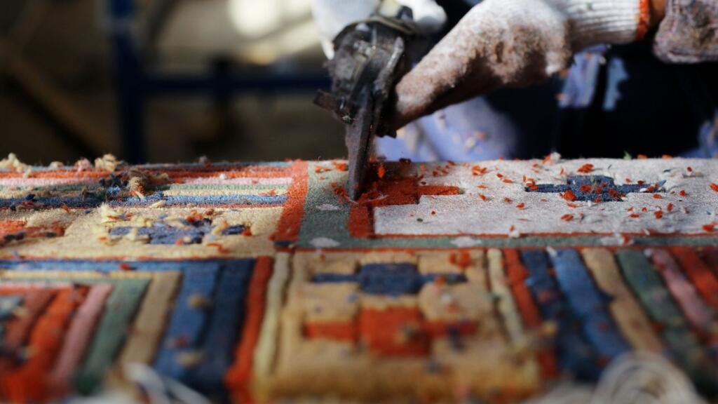 Close-up of a skilled worker crafting intricate patterns on a carpet, showcasing the craftsmanship of carpet manufacturers in UAE.