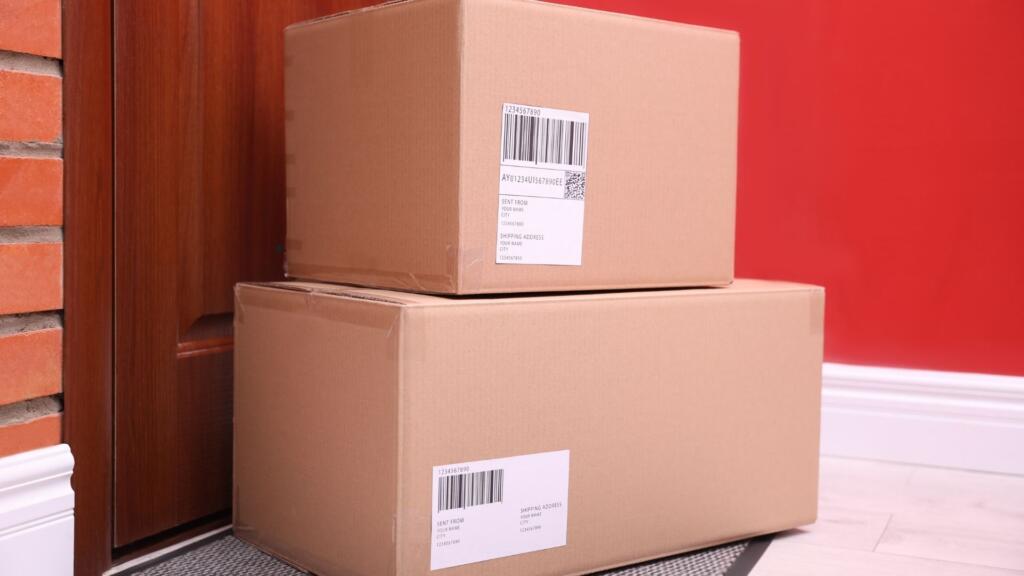 Cardboard boxes with shipping labels delivered to a doorstep, representing efficient delivery service from American Carpet Wholesalers in Georgia.