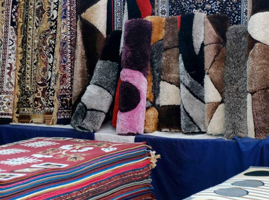 Display of various colorful and textured custom carpets and rugs in a store, showcasing diverse patterns and styles