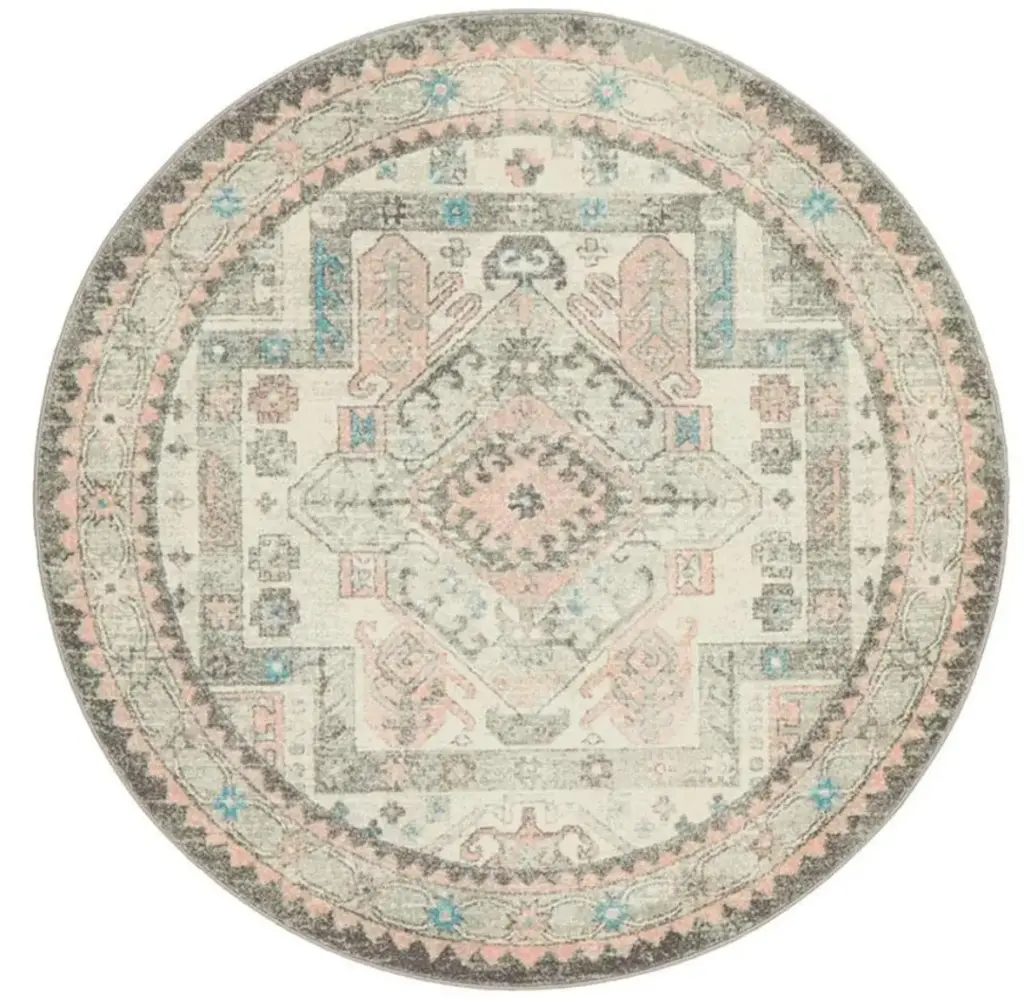 A circular rug with a faded, vintage-inspired medallion design in pastel pink, blue, and gray tones, featuring intricate detailing.